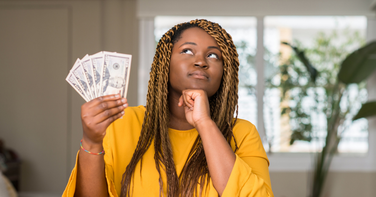 Woman thinking while holding money.
