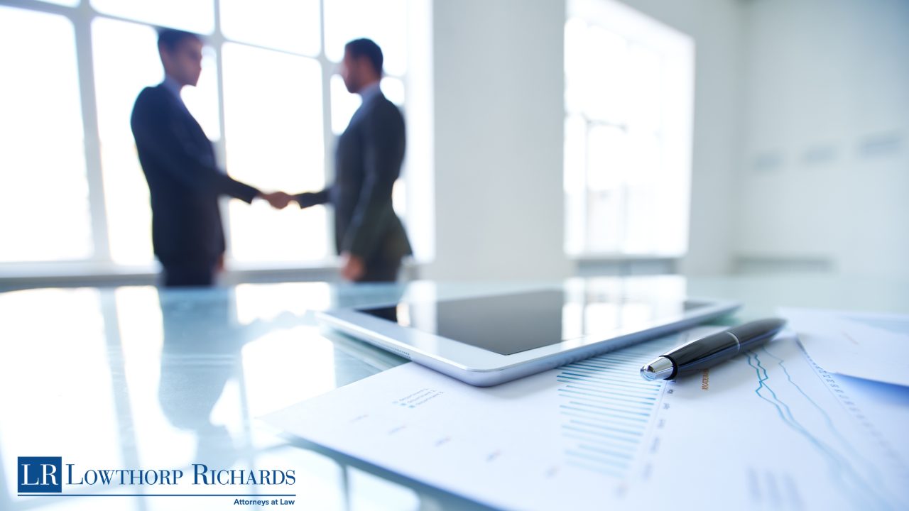 Business Partners shaking hands in front of papers after business succession
